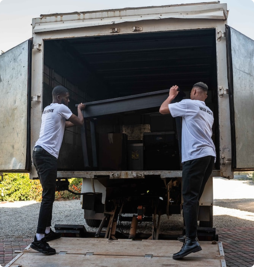 Two movers unloading a sofa from a truck.