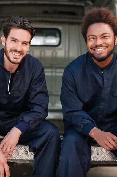 Two smiling men sitting and posing for the camera.